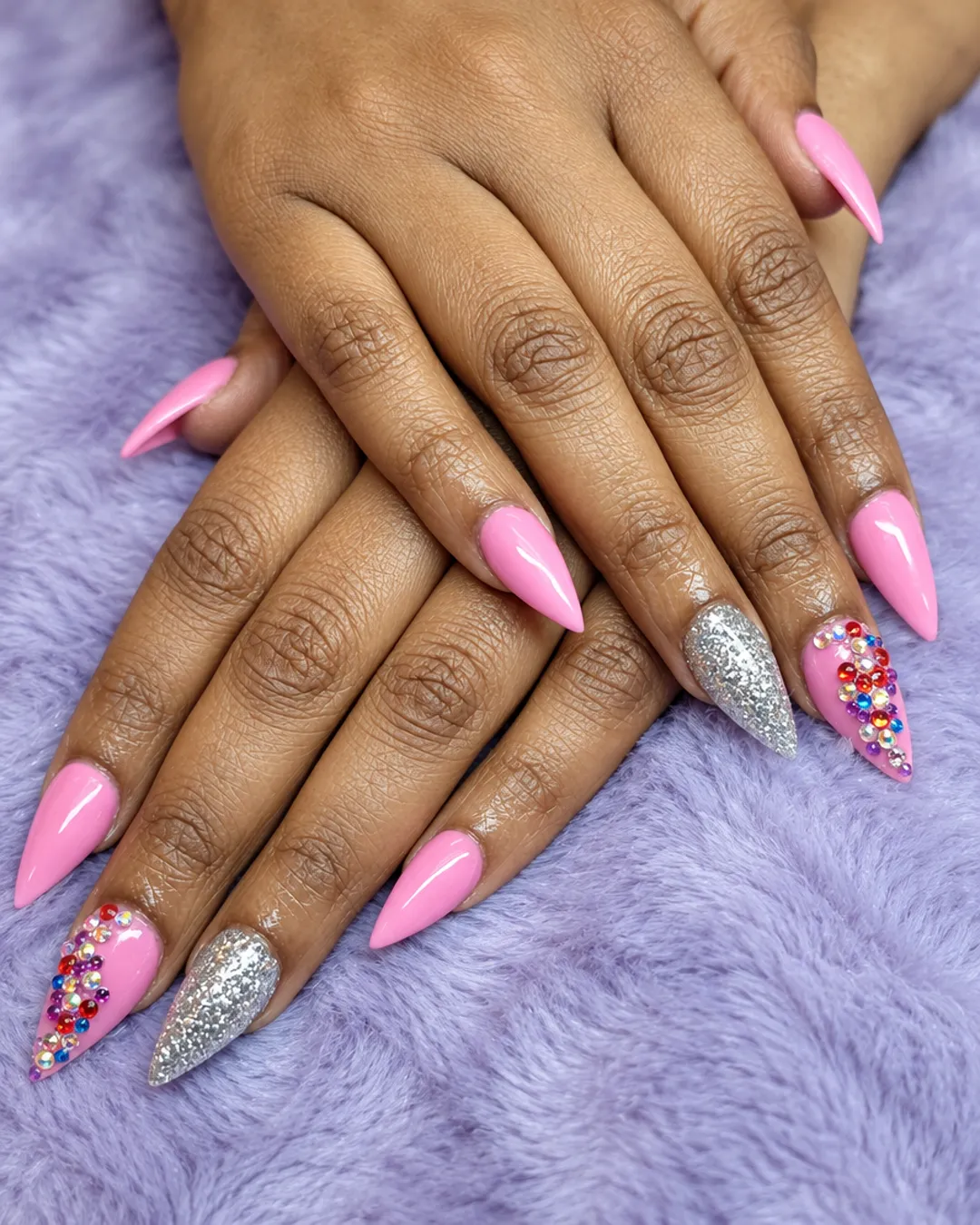 Pink stiletto nails with silver glitter and multicolor rhinestones
